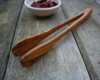 hand crafted olive wood tongs by the rustic dish